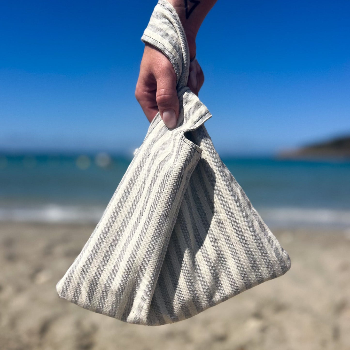 Grau weiß gestreifte Knot bag am Strand.