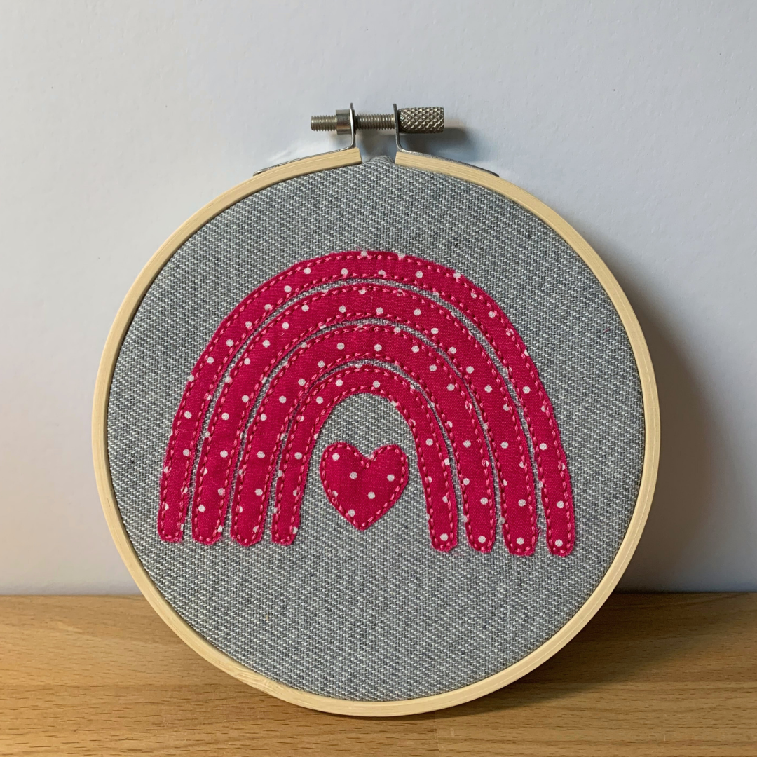 Gestickter Doodle Regenbogen in einen Stickrahmen eingespannt.